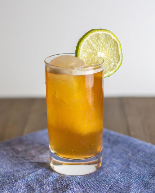 A BARE Pirate & Coke Zero-Proof cocktail in a glass with a lime wedge, made with BARE ZERO PROOF® Caribbean Gold Spiced Rum