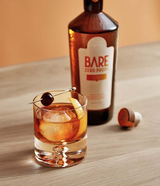 A BARE Old Fashioned Zero-Proof Cocktail with a bottle of BARE ZERO PROOF® Bourbon Whiskey.