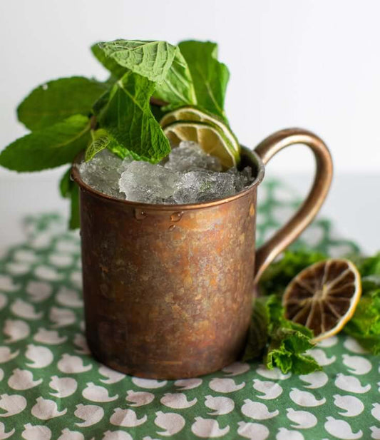 A BARE Mint Julep Zero-Proof cocktail in a mule mug on a table, made with BARE ZERO PROOF® Bourbon Whiskey.